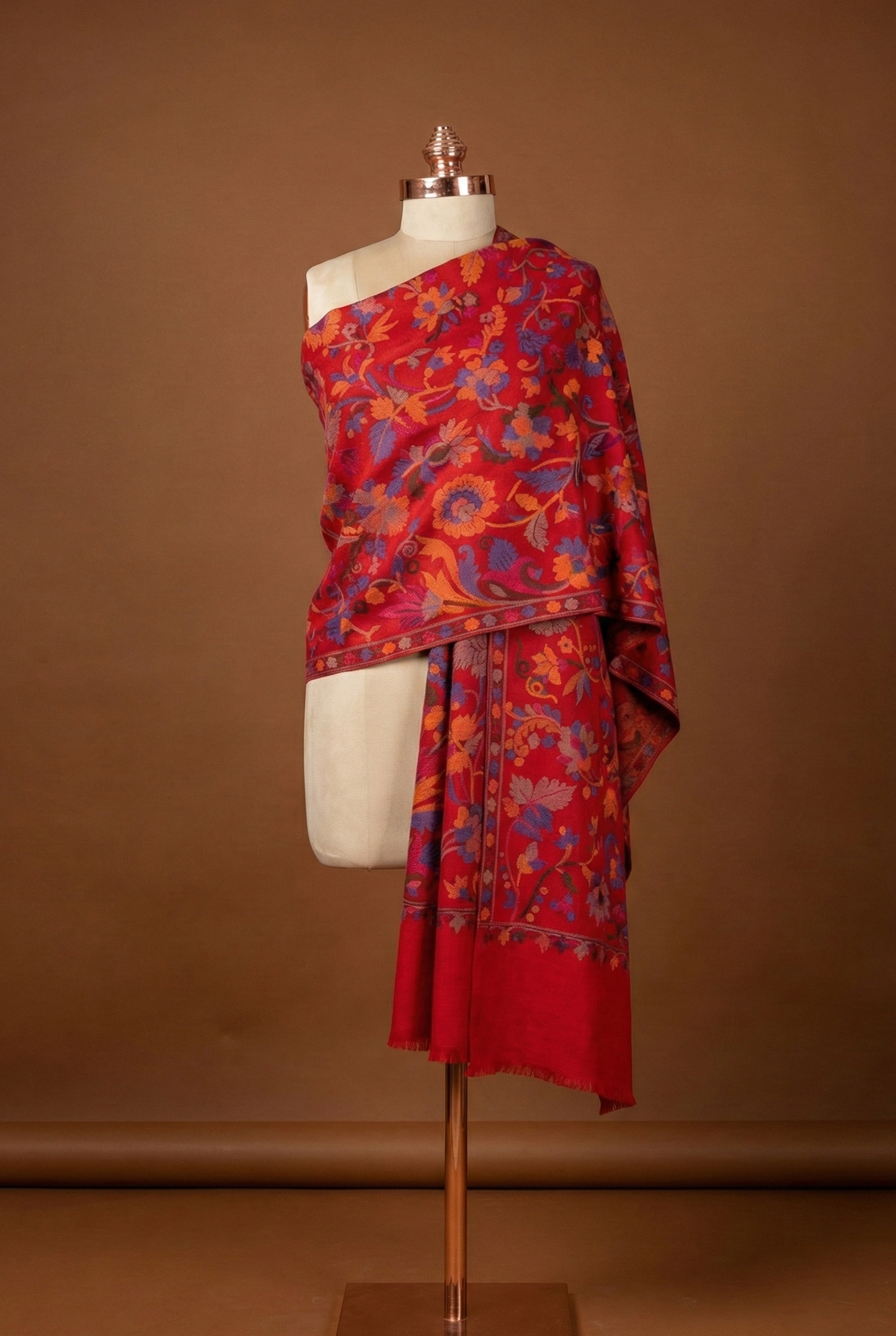 Red and orange patterned shawl  draped over a mannequin against a brown background